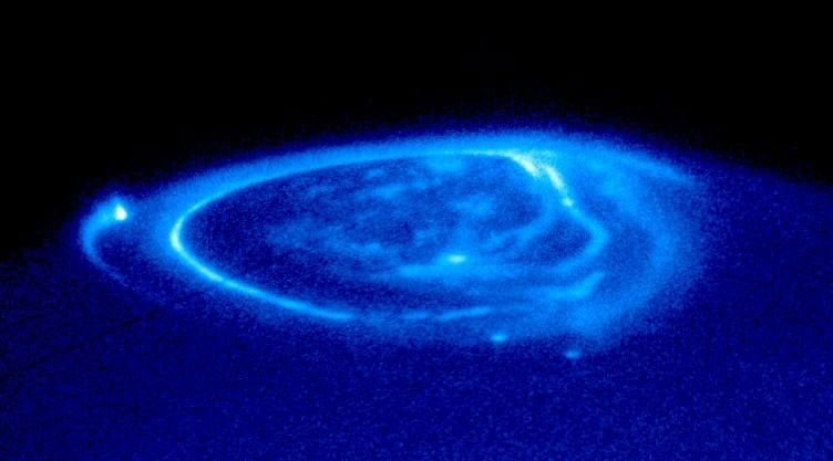 Jupiter: The Planet That Never Stopped Forming Real Hubble Space Telescope ultraviolet photograph of Jupiter's aurora showing the glowing magnetic footprints of its moons Io, Europa, and Ganymede